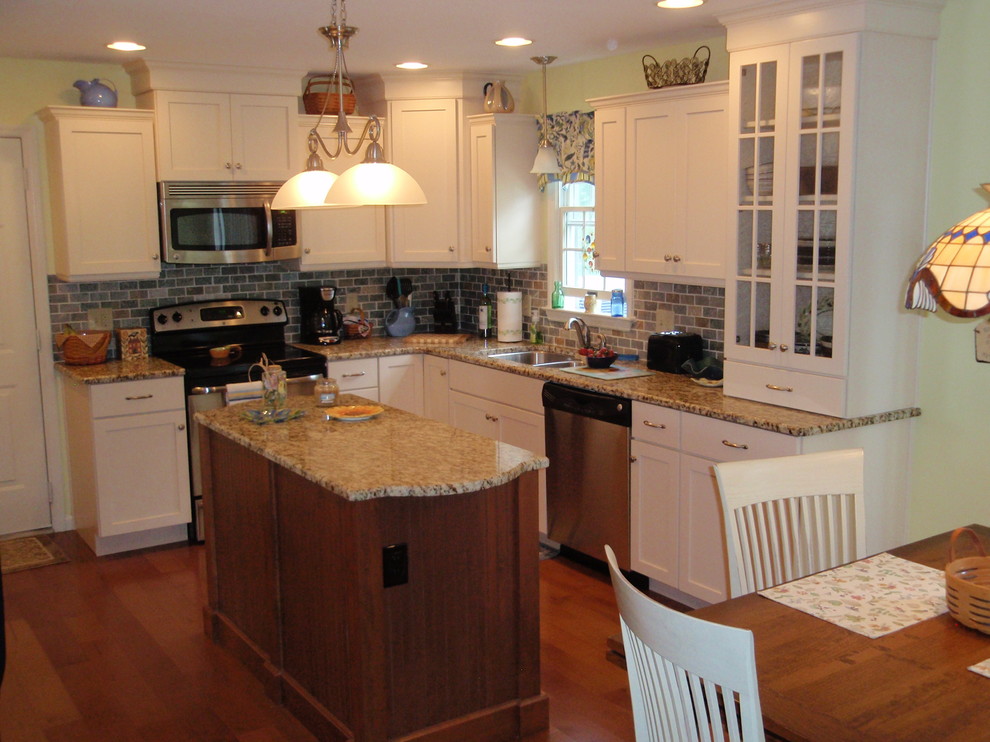 Example of a transitional l-shaped eat-in kitchen design with an undermount sink, shaker cabinets, white cabinets, granite countertops, gray backsplash, stone tile backsplash and stainless steel appliances