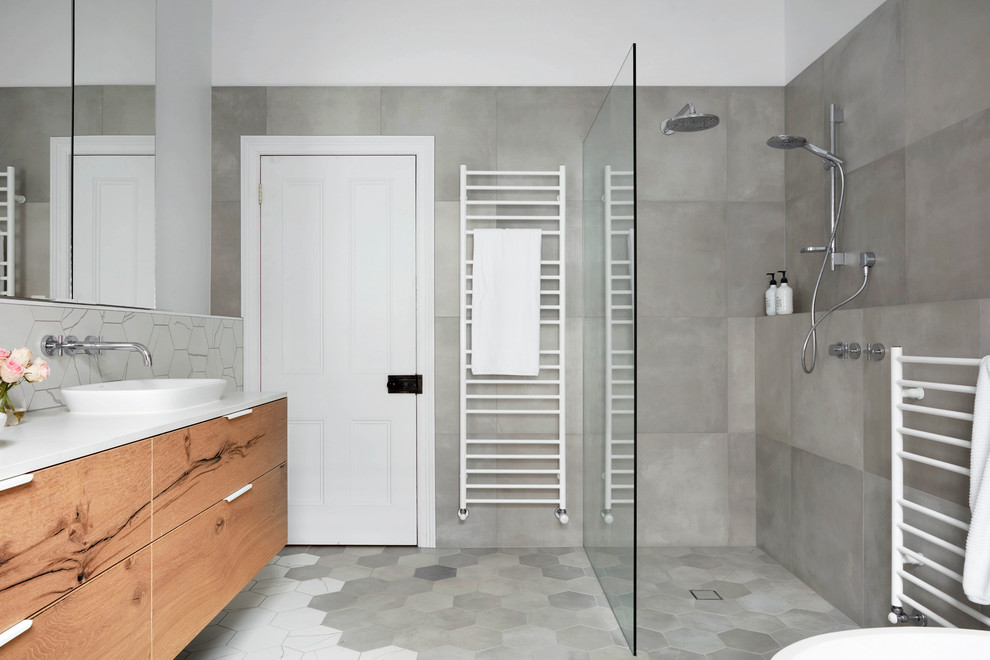 Large contemporary master bathroom in Melbourne with flat-panel cabinets, light wood cabinets, a freestanding tub, an open shower, gray tile, white tile, mosaic tile, white walls, mosaic tile floors, a vessel sink and solid surface benchtops.