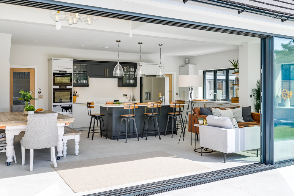 Design ideas for a medium sized industrial open plan kitchen in Sussex with an integrated sink, shaker cabinets, grey cabinets, quartz worktops, stainless steel appliances, porcelain flooring, an island, white floors and white worktops.