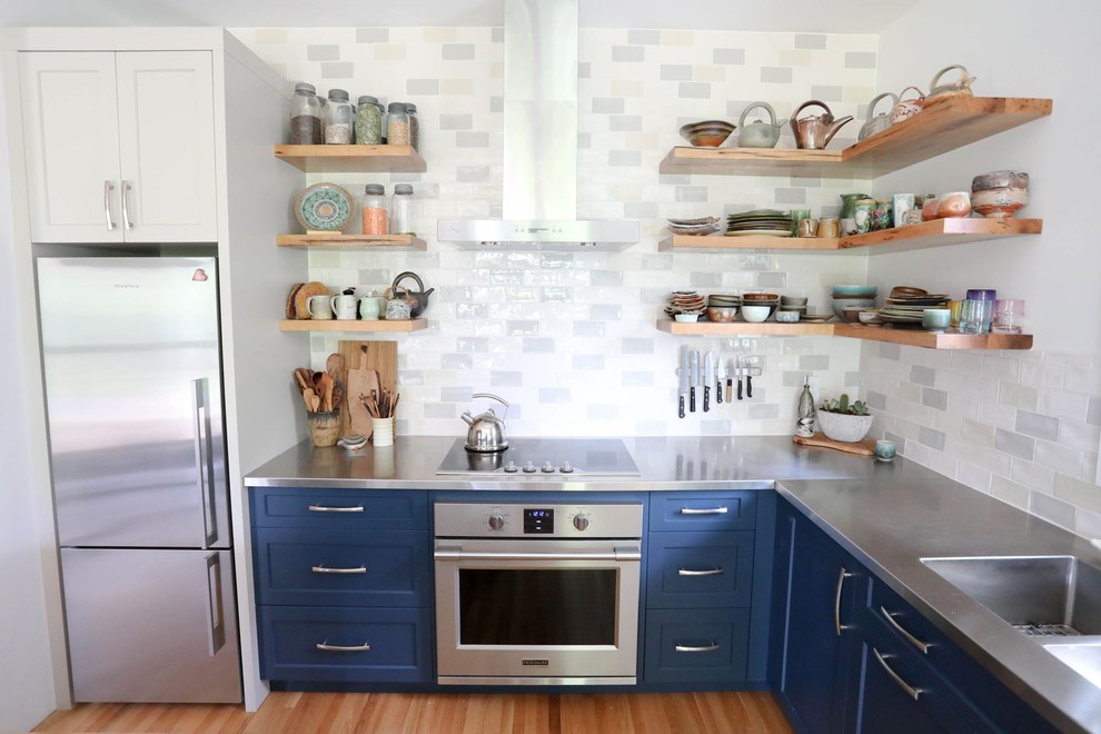 Inspiration for a mid-sized transitional l-shaped light wood floor and beige floor open concept kitchen remodel with an integrated sink, shaker cabinets, blue cabinets, stainless steel countertops, ceramic backsplash, stainless steel appliances, an island and gray countertops