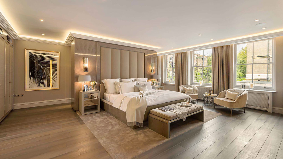 Expansive transitional master bedroom in London with beige walls, medium hardwood floors and brown floor.
