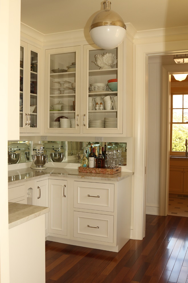 Design ideas for a traditional kitchen pantry in Other with glass-front cabinets, white cabinets, mirror splashback and medium hardwood floors.