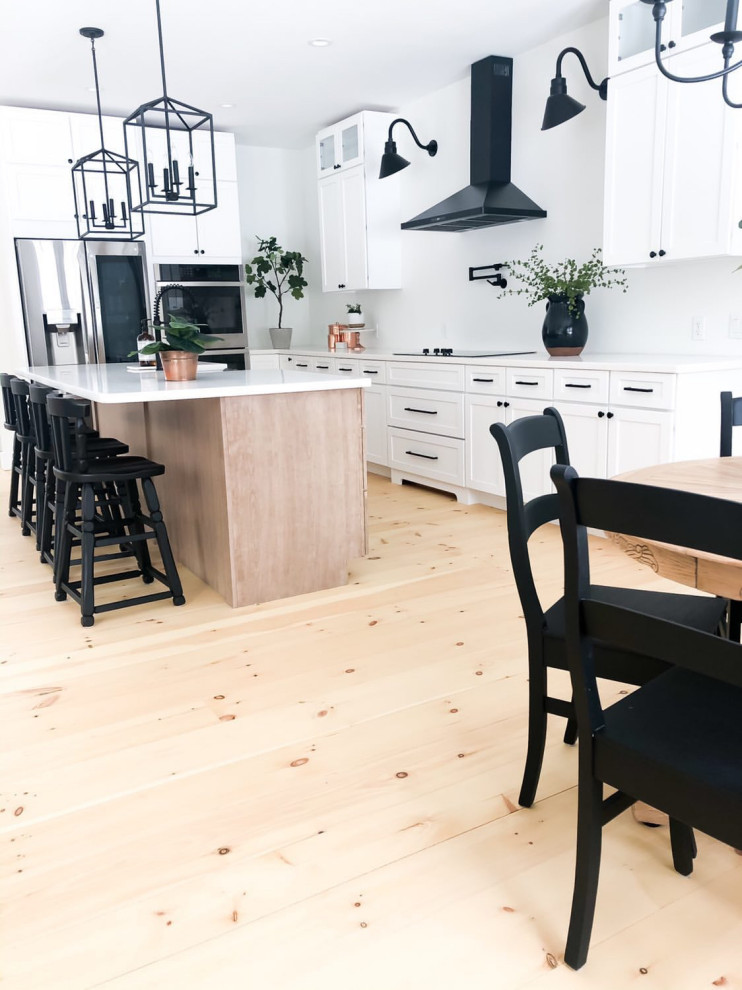 Inspiration for a mid-sized country l-shaped eat-in kitchen in Tampa with a farmhouse sink, recessed-panel cabinets, white cabinets, granite benchtops, white splashback, stainless steel appliances, light hardwood floors, with island and white benchtop.