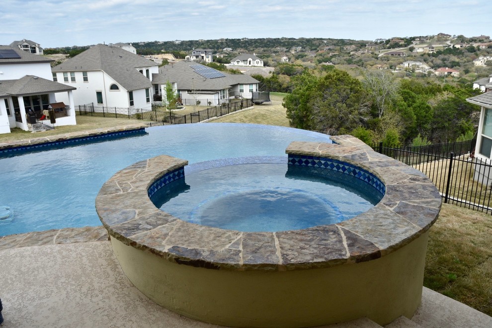 Example of a mid-sized transitional backyard concrete and custom-shaped infinity hot tub design in Austin