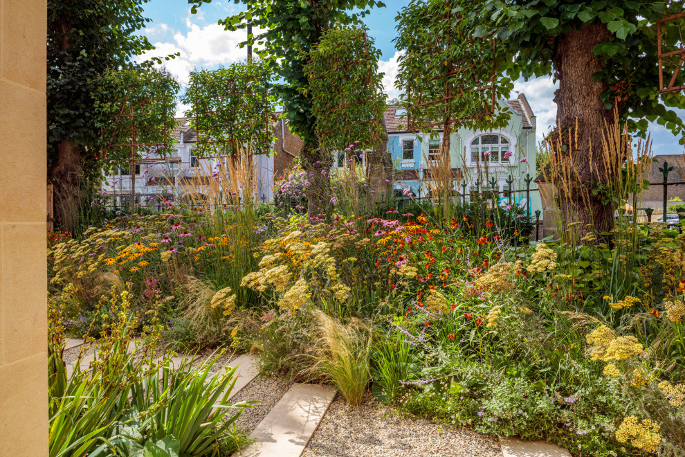 Ejemplo de jardín de secano contemporáneo de tamaño medio en verano en patio delantero con parterre de flores, exposición total al sol, adoquines de piedra natural y con metal
