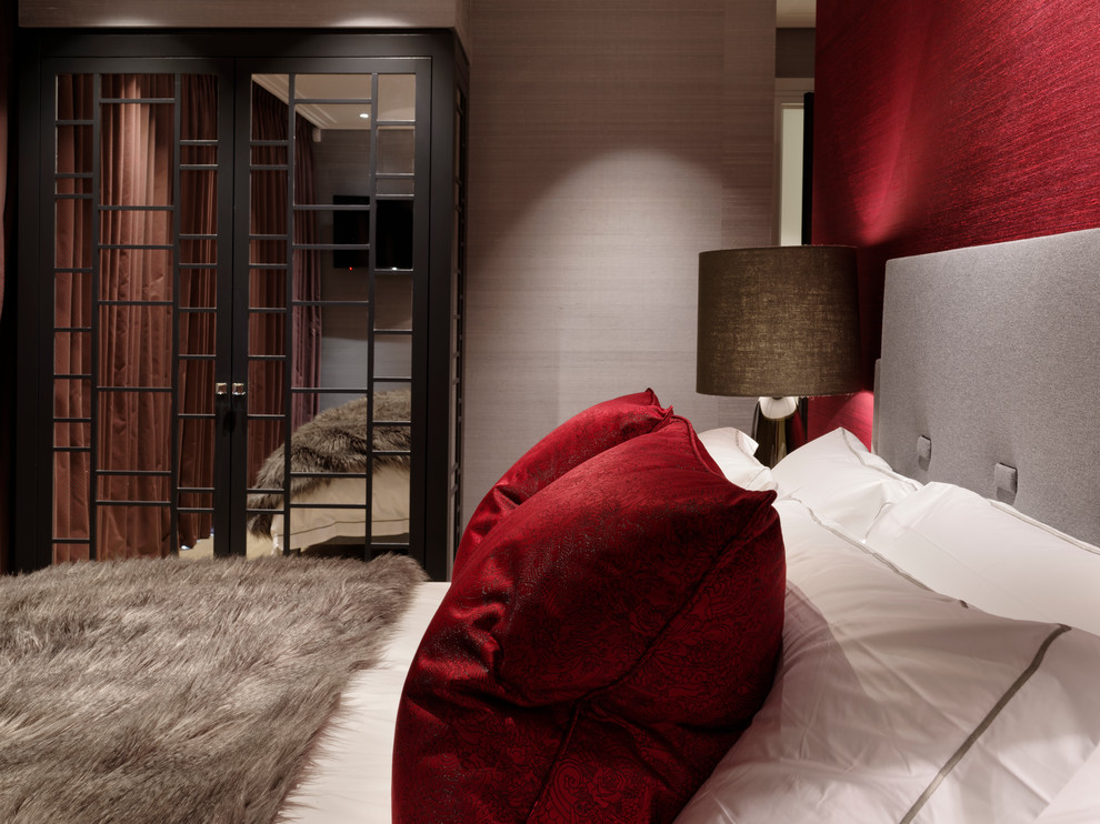 This is an example of a mid-sized contemporary master bedroom in London with red walls.
