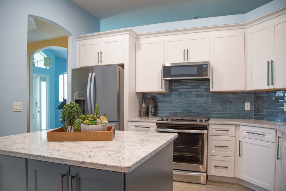 Design ideas for a mid-sized traditional u-shaped separate kitchen in Orlando with an undermount sink, shaker cabinets, blue cabinets, quartz benchtops, blue splashback, glass tile splashback, stainless steel appliances, vinyl floors, with island, beige floor and blue benchtop.