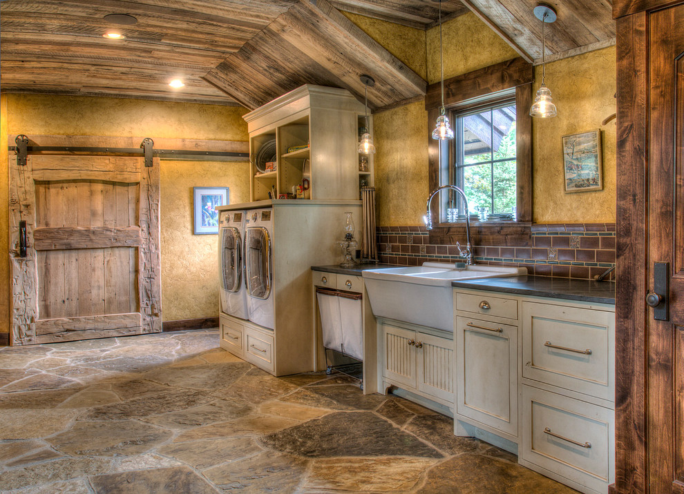 Large country galley dedicated laundry room in Minneapolis with a double-bowl sink, beaded inset cabinets, white cabinets, granite benchtops, yellow walls, slate floors, a side-by-side washer and dryer, multi-coloured floor and black benchtop.