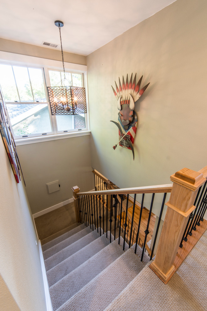 This is an example of a mid-sized arts and crafts carpeted u-shaped staircase in Denver with carpet risers and metal railing.