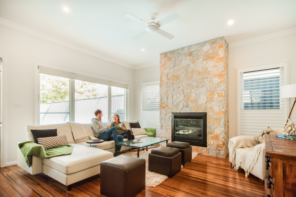 Mid-sized contemporary open concept living room in Sydney with white walls, medium hardwood floors, a standard fireplace, a stone fireplace surround and no tv.