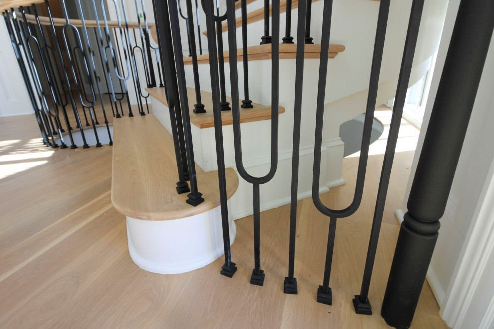 Expansive classic wood curved mixed railing staircase in DC Metro with wood risers and wainscoting.