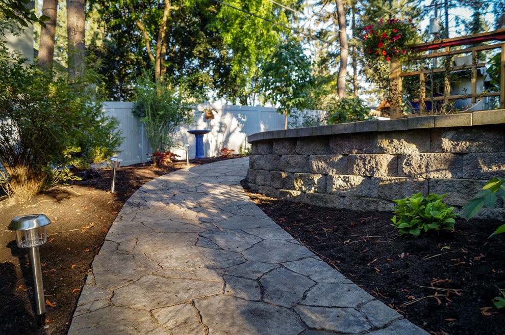 This is an example of a mid-sized rustic partial sun backyard concrete paver retaining wall landscape.