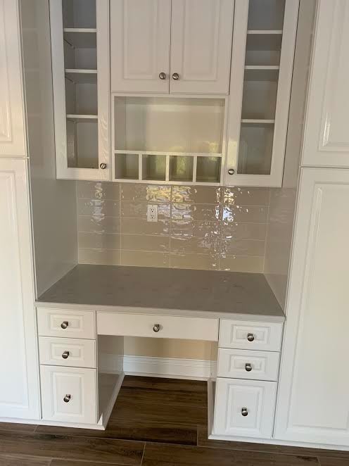 Example of a transitional l-shaped kitchen design in New York with raised-panel cabinets, white cabinets, beige backsplash and ceramic backsplash