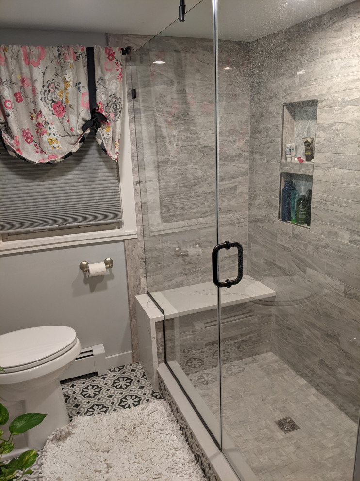 Cette photo montre une douche en alcôve chic avec un carrelage gris, des carreaux de porcelaine, carreaux de ciment au sol, une cabine de douche à porte battante et un banc de douche.