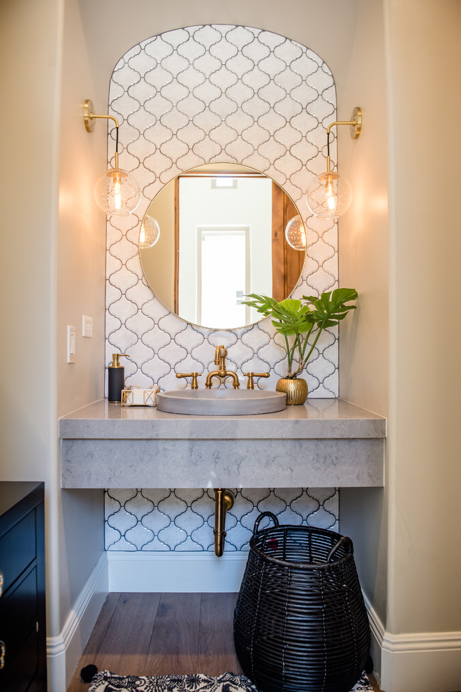 Mid-sized eclectic powder room in Phoenix with white tile, ceramic tile, grey walls, medium hardwood floors, a vessel sink, engineered quartz benchtops and grey benchtops.