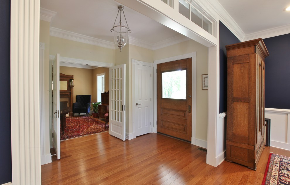 Example of a large light wood floor and brown floor front door design with a brown front door