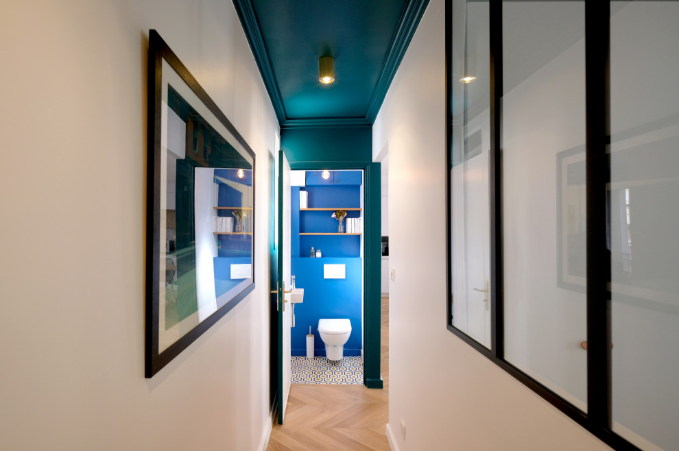 Diseño de recibidores y pasillos minimalistas de tamaño medio con paredes azules, suelo de madera clara y suelo beige