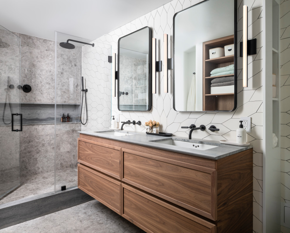Design ideas for a mid-sized contemporary master bathroom in New York with recessed-panel cabinets, brown cabinets, an alcove shower, a one-piece toilet, white tile, ceramic tile, white walls, marble floors, an undermount sink, marble benchtops, grey floor, a hinged shower door, grey benchtops, a niche, a double vanity and a floating vanity.