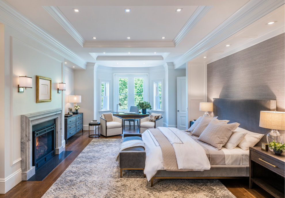 This is an example of a transitional master bedroom in Boston with white walls, medium hardwood floors, a standard fireplace, a stone fireplace surround, recessed and wallpaper.
