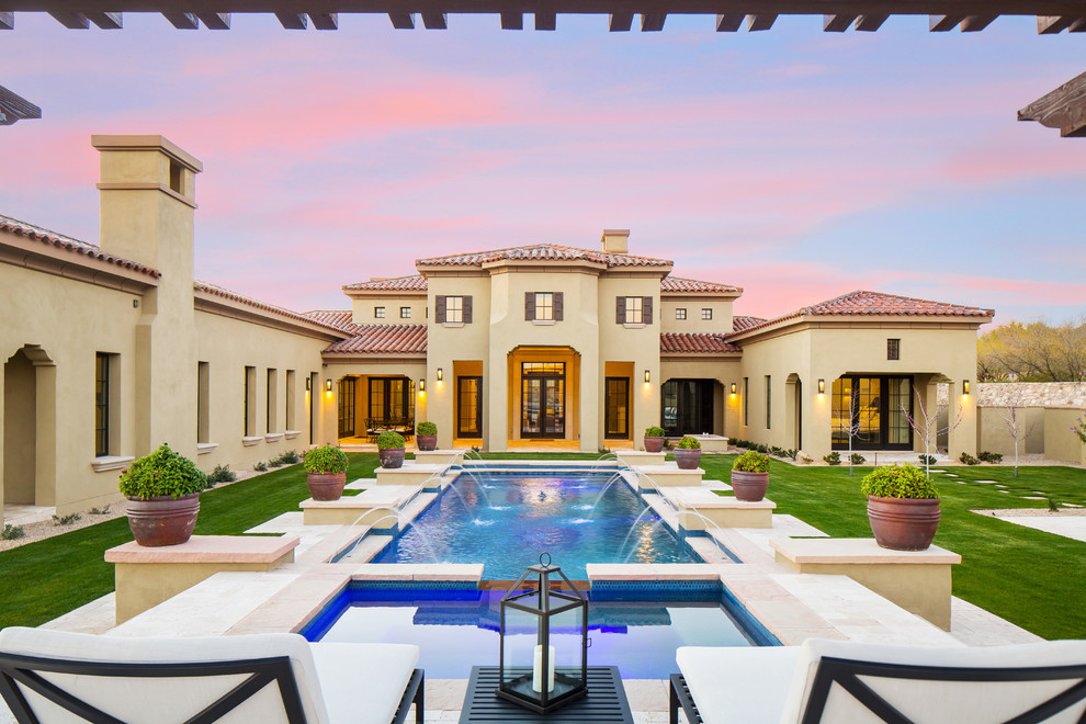 Photo of a large mediterranean two-storey stucco beige house exterior in Phoenix with a hip roof and a tile roof.