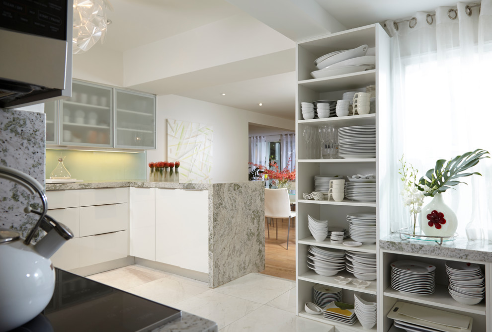 This is an example of a mid-sized contemporary u-shaped open plan kitchen in Miami with a triple-bowl sink, glass-front cabinets, white cabinets, granite benchtops, green splashback, glass sheet splashback, stainless steel appliances and marble floors.