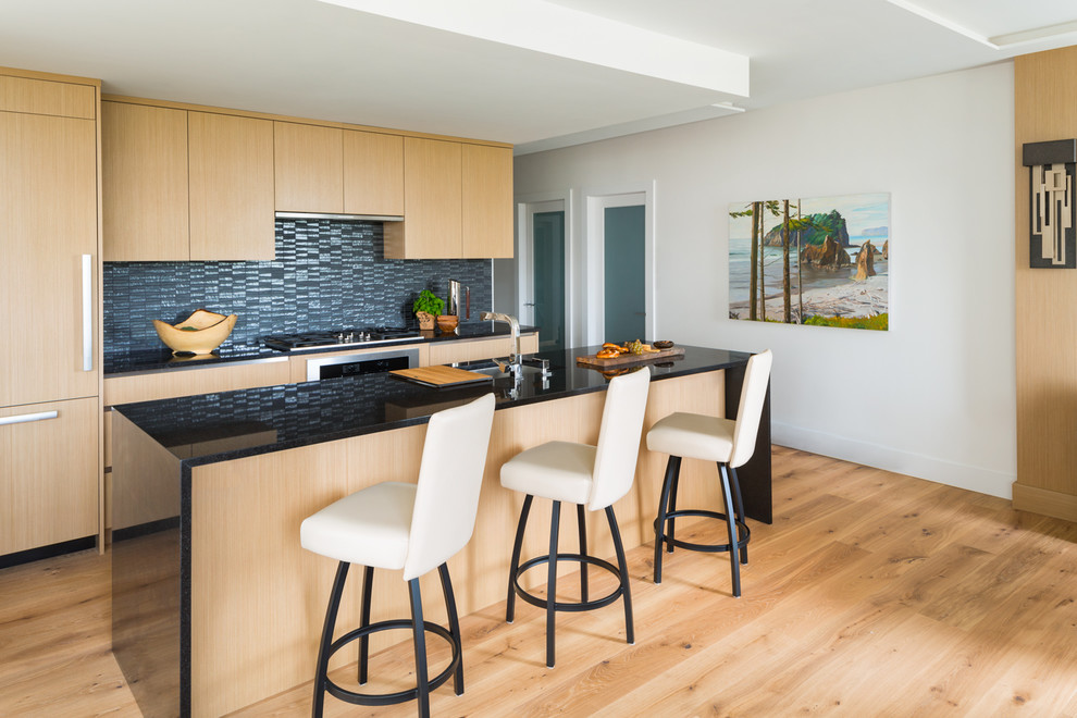 Design ideas for a small contemporary galley eat-in kitchen in Vancouver with an undermount sink, flat-panel cabinets, medium wood cabinets, granite benchtops, black splashback, glass tile splashback, panelled appliances, medium hardwood floors, with island and black benchtop.