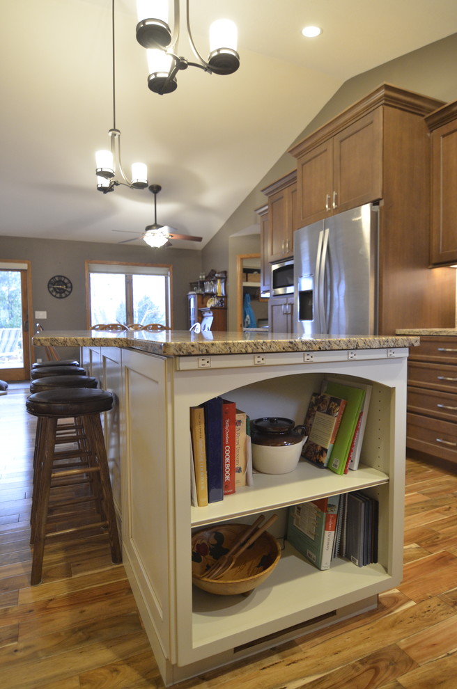 Transitional l-shaped medium tone wood floor open concept kitchen photo in Minneapolis with flat-panel cabinets, beige cabinets, granite countertops, beige backsplash, glass tile backsplash, stainless steel appliances and an island