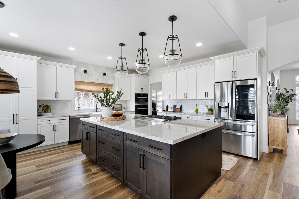 Inspiration for a transitional vinyl floor and brown floor kitchen remodel with a farmhouse sink, shaker cabinets, white cabinets, quartzite countertops, white backsplash and stainless steel appliances