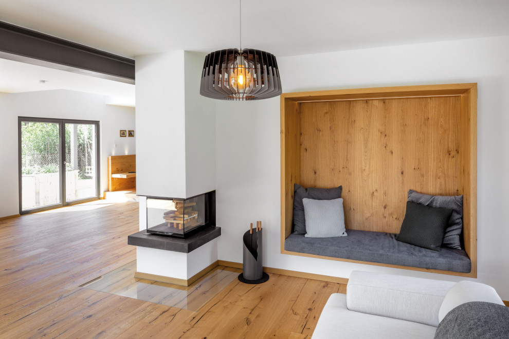 ミュンヘンにあるトラディショナルスタイルのおしゃれなリビング (淡色無垢フローリング、コーナー設置型暖炉、漆喰の暖炉まわり、茶色い床) の写真