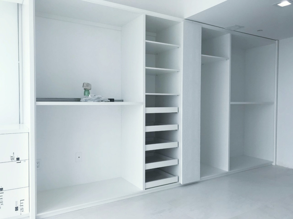Inspiration for a large modern gender neutral built-in wardrobe in Miami with flat-panel cabinets and white cabinets.