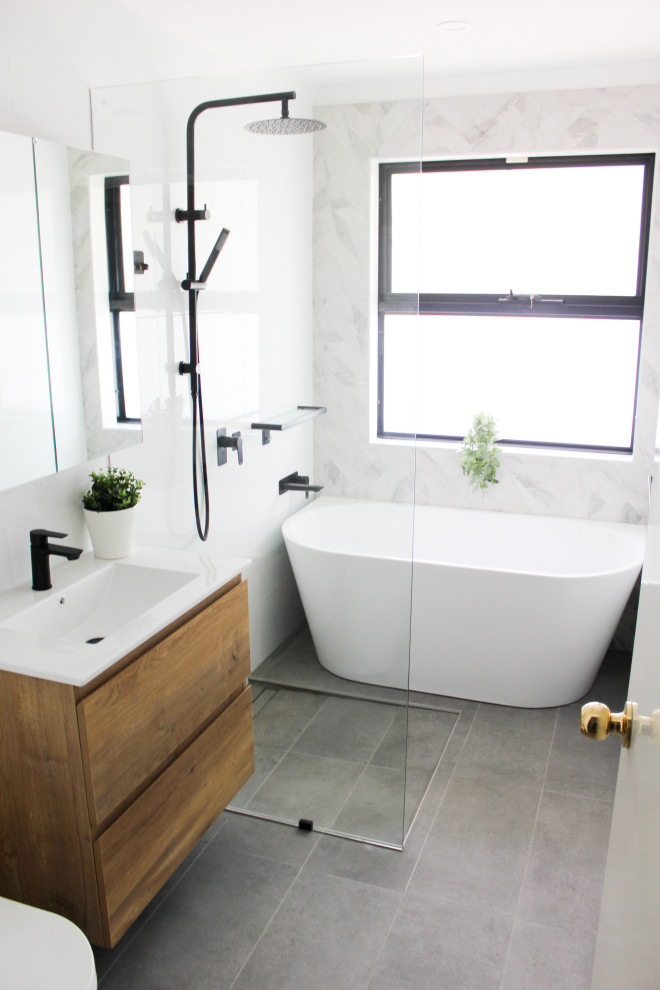 Mid-sized modern master bathroom in Perth with flat-panel cabinets, light wood cabinets, a freestanding tub, an open shower, a one-piece toilet, white tile, ceramic tile, white walls, porcelain floors, an integrated sink, engineered quartz benchtops, grey floor, an open shower and white benchtops.