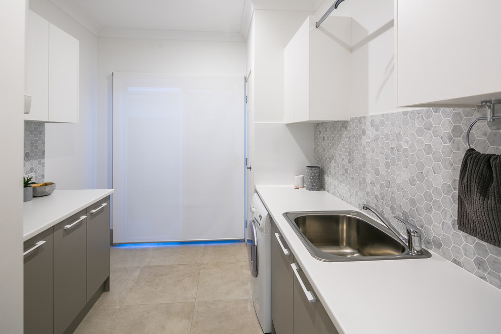 Large contemporary galley utility room in Brisbane with a drop-in sink, laminate benchtops, porcelain floors, white walls, a stacked washer and dryer, beige floor and white benchtop.