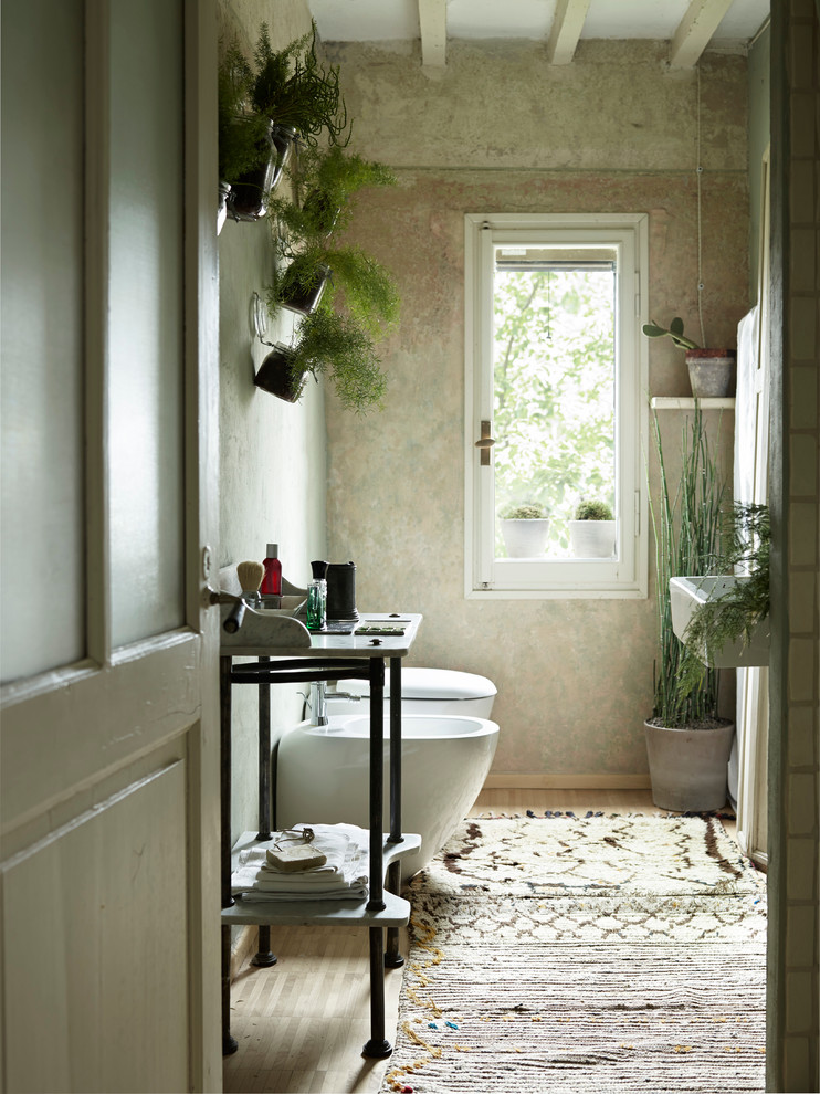 Inspiration for a small country powder room in Other with green walls, light hardwood floors, a wall-mount toilet, a wall-mount sink and beige floor.