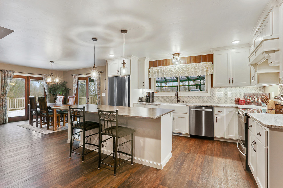 Large elegant eat-in kitchen photo with a farmhouse sink, stainless steel appliances and an island