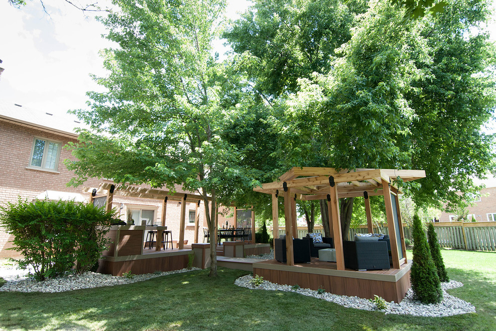 This is an example of a mid-sized country backyard deck in Toronto with an outdoor kitchen and a pergola.