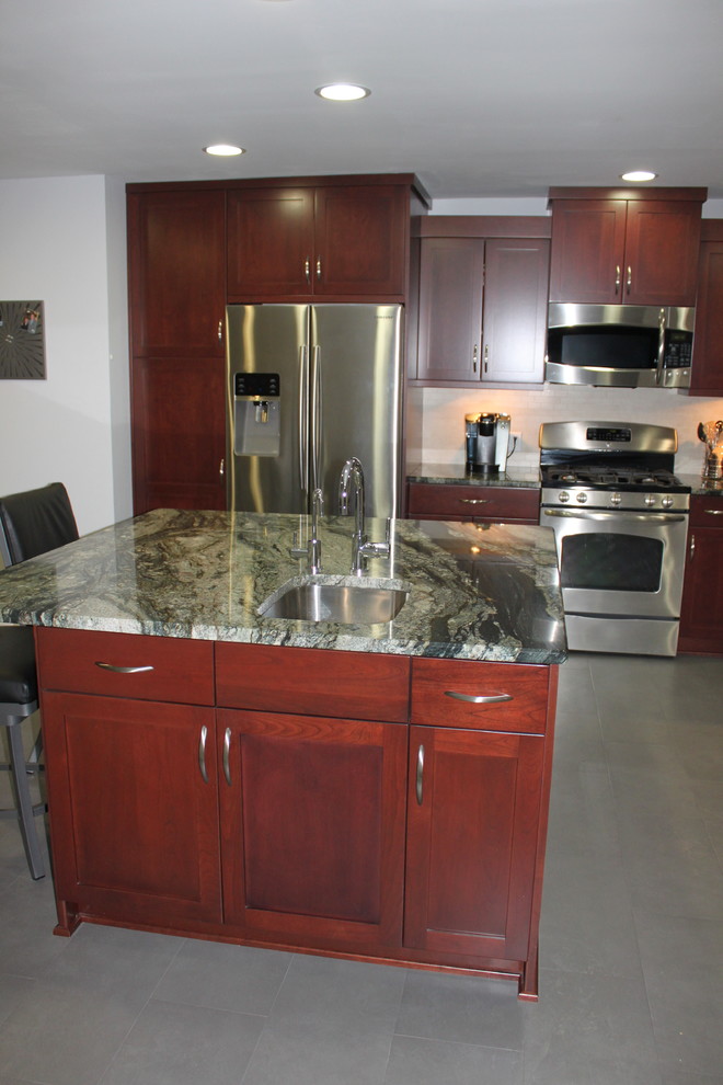 Example of a transitional eat-in kitchen design in New York with an undermount sink, shaker cabinets, granite countertops, porcelain backsplash and stainless steel appliances