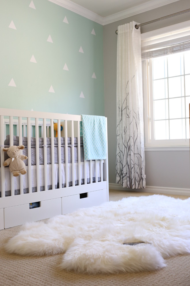 This is an example of a transitional gender-neutral nursery in San Diego with blue walls, carpet and beige floor.