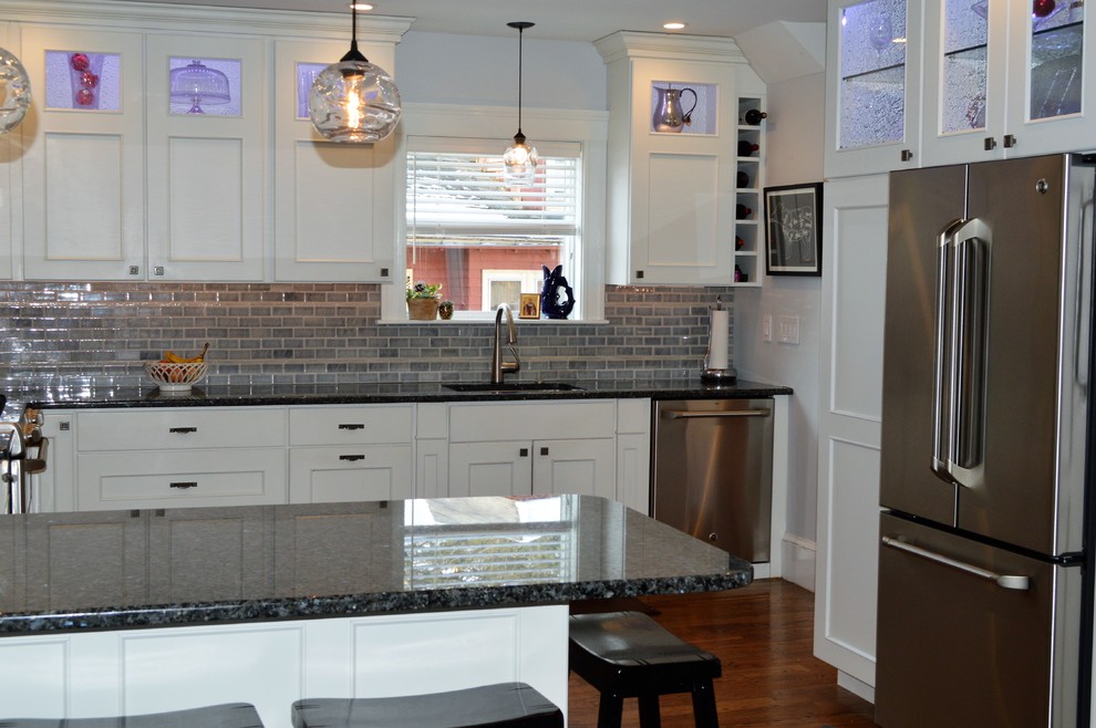 Example of a mid-sized transitional l-shaped medium tone wood floor eat-in kitchen design in Boston with an undermount sink, recessed-panel cabinets, white cabinets, granite countertops, gray backsplash, cement tile backsplash, stainless steel appliances, a peninsula and blue countertops