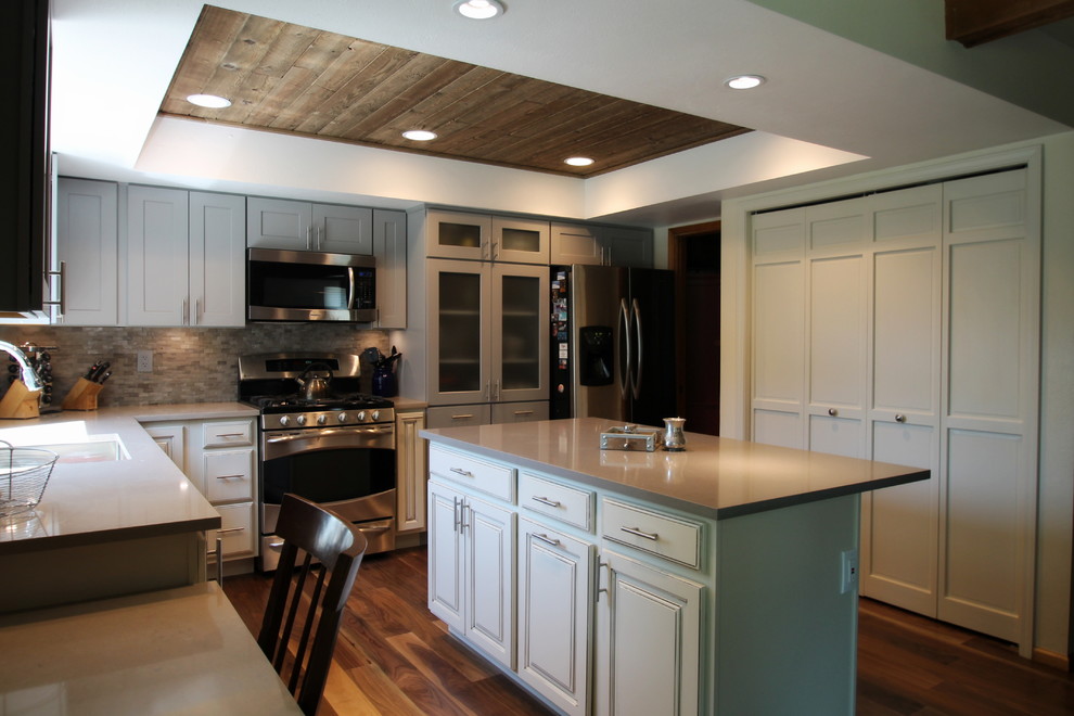 Inspiration for a large transitional l-shaped medium tone wood floor eat-in kitchen remodel in Denver with an undermount sink, shaker cabinets, gray cabinets, quartz countertops, gray backsplash, stone tile backsplash, stainless steel appliances and an island