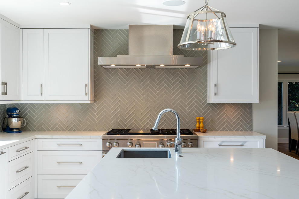 Expansive transitional u-shaped kitchen in Los Angeles with a drop-in sink, shaker cabinets, white cabinets, quartzite benchtops, grey splashback, glass tile splashback, stainless steel appliances, medium hardwood floors, with island, brown floor and white benchtop.