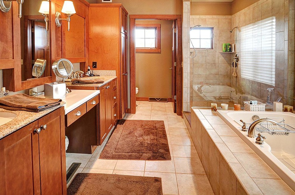 Photo of a mid-sized contemporary 3/4 bathroom in Milwaukee with recessed-panel cabinets, medium wood cabinets, a drop-in tub, an alcove shower, a two-piece toilet, beige tile, ceramic tile, beige walls, ceramic floors, an undermount sink and granite benchtops.