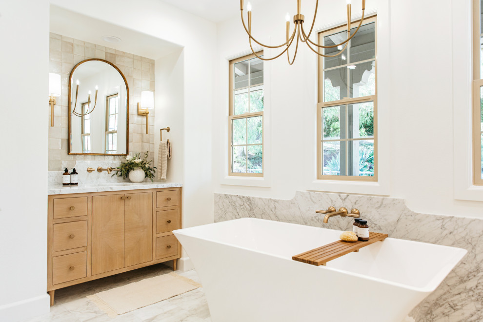 Aménagement d'une salle de bain classique en bois clair avec un placard à porte plane, une baignoire indépendante, un carrelage beige, un mur blanc, un lavabo encastré, un sol gris, un plan de toilette blanc, meuble simple vasque et meuble-lavabo encastré.