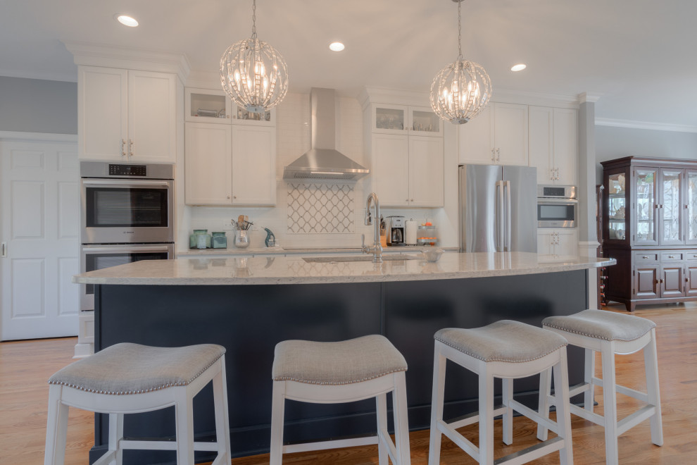 Inspiration for a mid-sized transitional galley medium tone wood floor eat-in kitchen remodel with an undermount sink, flat-panel cabinets, white cabinets, quartz countertops, white backsplash, subway tile backsplash, stainless steel appliances, an island and white countertops