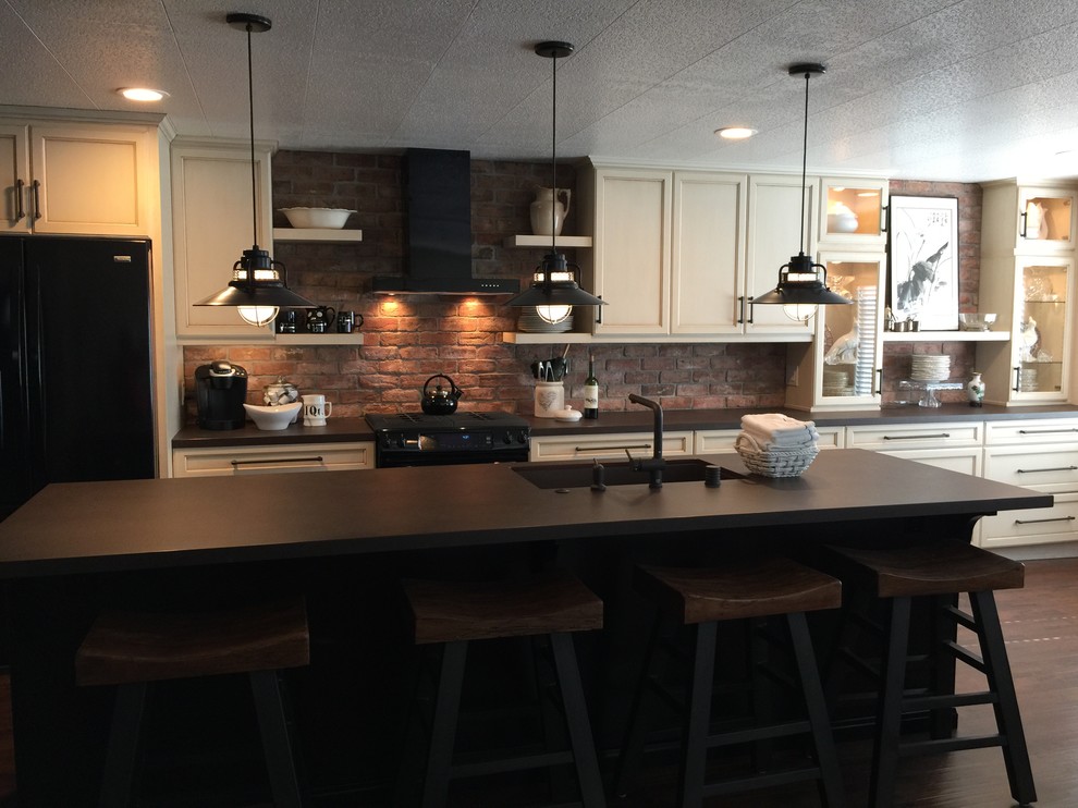 This is an example of a mid-sized industrial single-wall open plan kitchen in Los Angeles with a single-bowl sink, recessed-panel cabinets, distressed cabinets, quartzite benchtops, red splashback, subway tile splashback, black appliances, dark hardwood floors and with island.