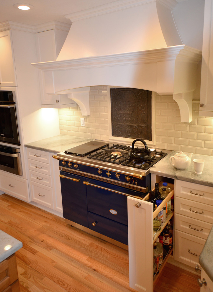 Eat-in kitchen - transitional u-shaped eat-in kitchen idea in Portland with a farmhouse sink, white cabinets, white backsplash, stainless steel appliances, shaker cabinets, quartzite countertops and porcelain backsplash