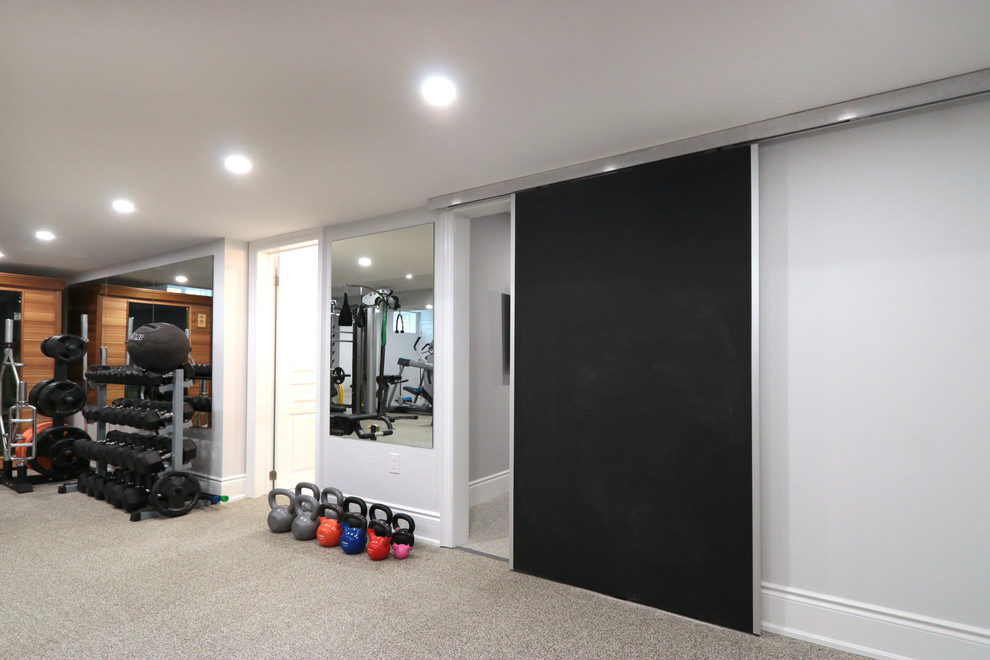 Photo of a large modern home weight room in Toronto with white walls, carpet and grey floor.