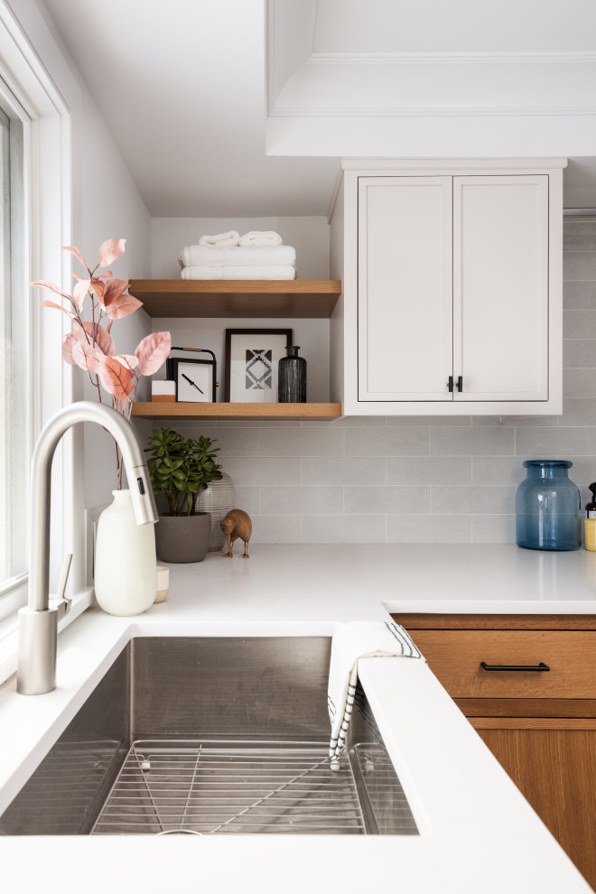 This is an example of a mid-sized transitional l-shaped utility room in New York with a drop-in sink, beaded inset cabinets, white cabinets, solid surface benchtops, white walls, a side-by-side washer and dryer, grey floor and white benchtop.