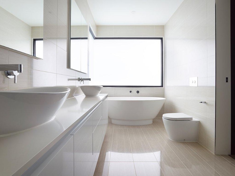 Contemporary master bathroom in Melbourne with flat-panel cabinets, white cabinets, a freestanding tub, a wall-mount toilet, beige tile, porcelain tile, beige walls, porcelain floors, a vessel sink and engineered quartz benchtops.