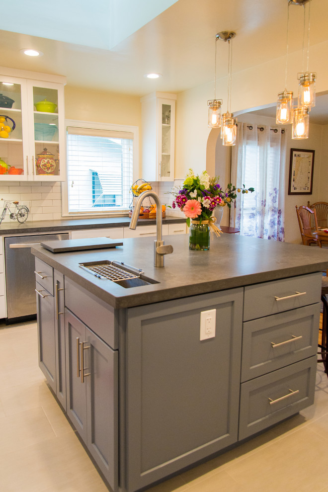 Transitional porcelain tile kitchen photo in Sacramento with a farmhouse sink, shaker cabinets, white cabinets, white backsplash, subway tile backsplash, stainless steel appliances and an island