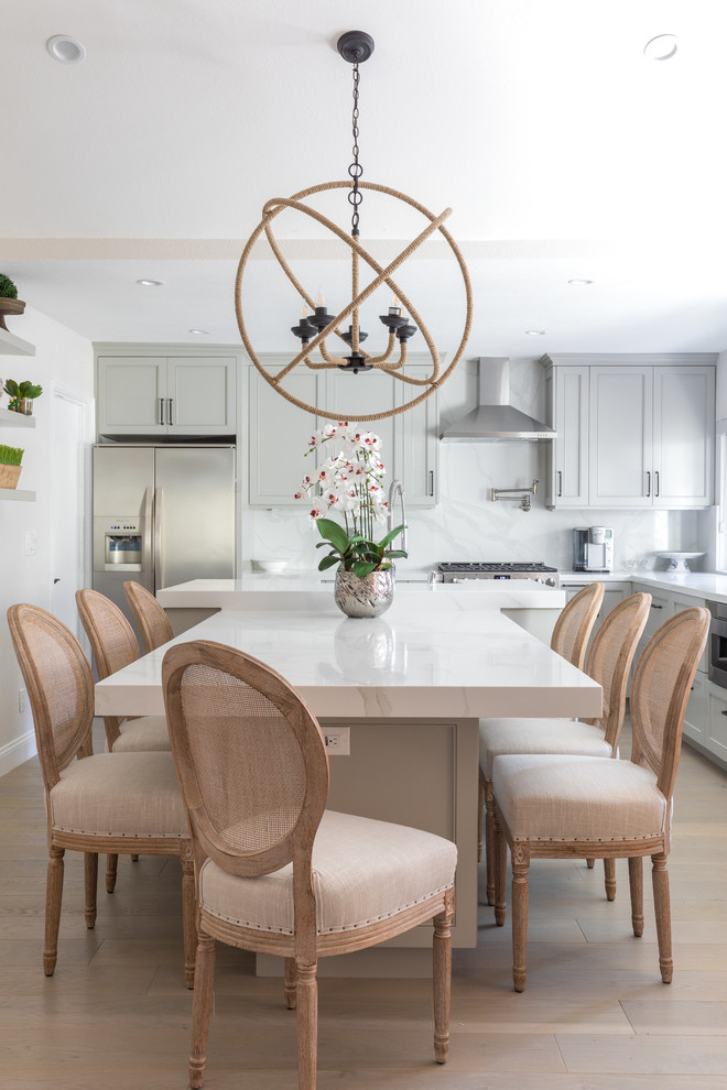 Mid-sized trendy u-shaped light wood floor and brown floor open concept kitchen photo in Orange County with gray cabinets, quartz countertops, white backsplash, marble backsplash, stainless steel appliances, an island, white countertops, a farmhouse sink and recessed-panel cabinets